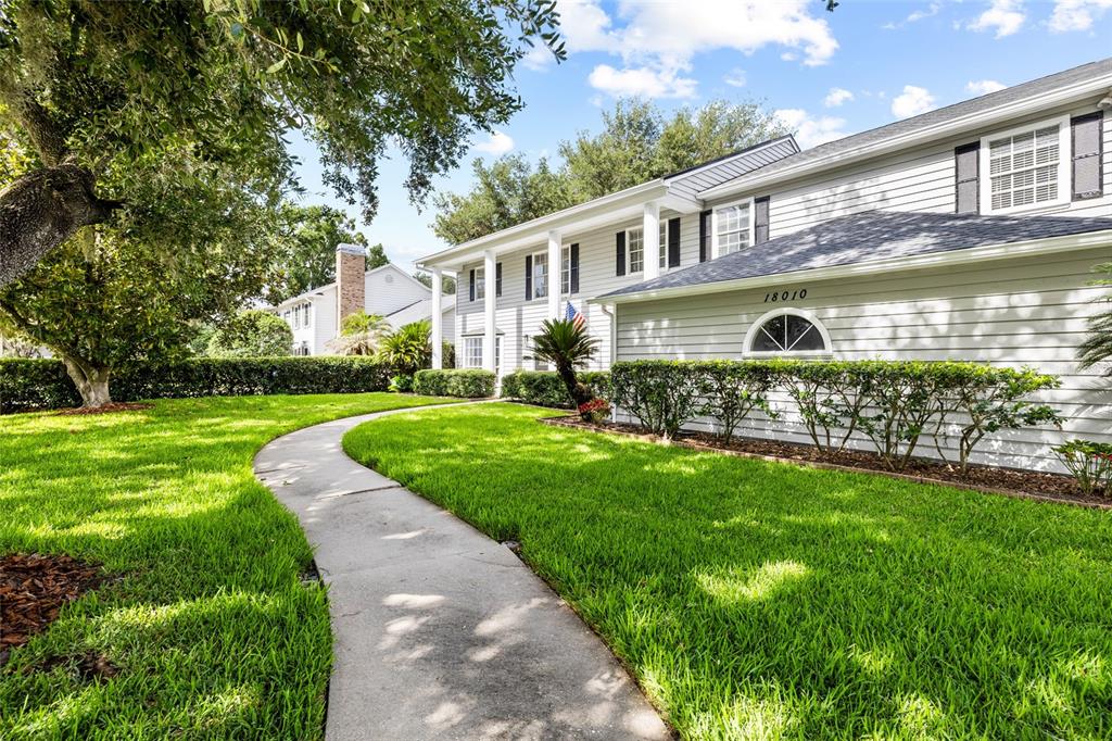 A two-story house with light gray siding and a curved walkway through the front lawn — 18010 CLEAR LAKE DRIVE, LUTZ, FL