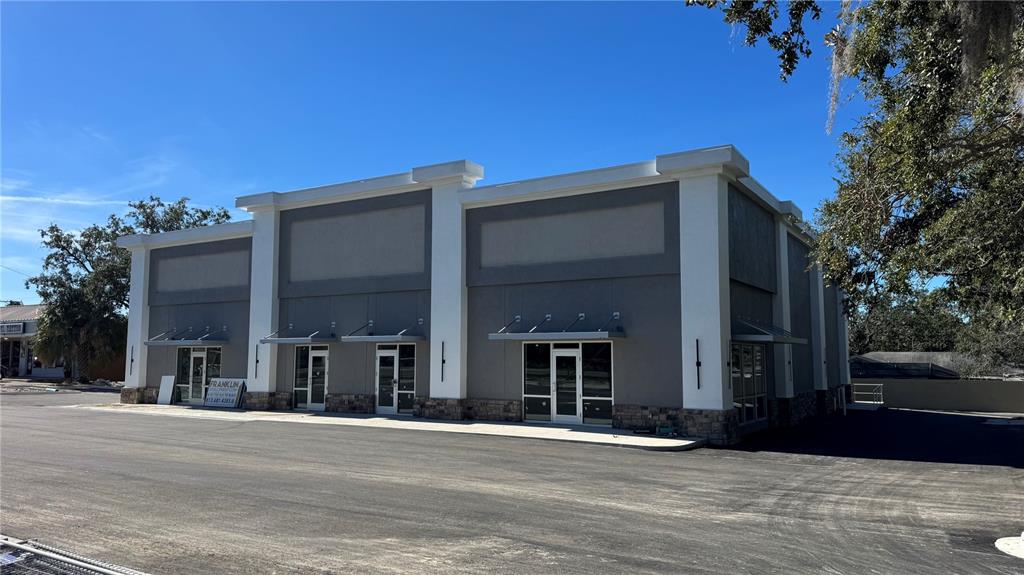 A modern commercial building features gray exterior walls, white columns, and multiple glass entry doors — 11210 N 30TH STREET, TAMPA, FL