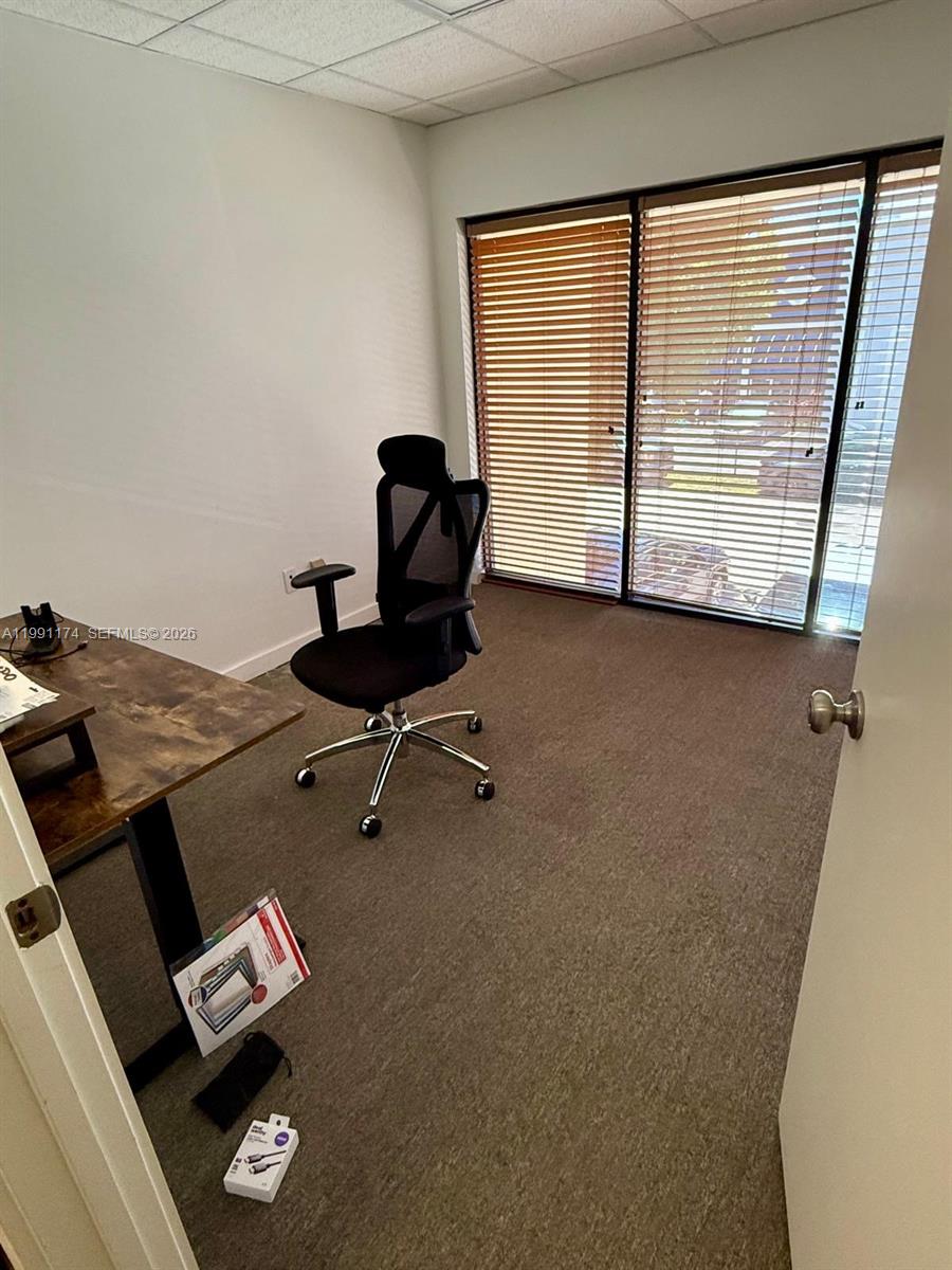 An office room features a desk, a black ergonomic chair, and large windows with blinds — 12016 SW 132nd Ct, Miami FL 33186, MIAMI, FL