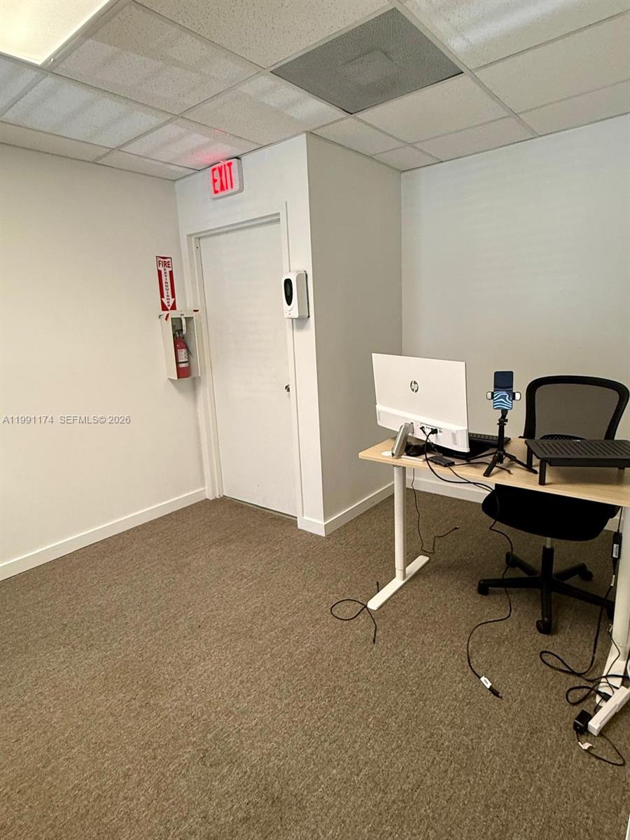 An office room features a desk with a computer, a chair, and an exit door — 12016 SW 132nd Ct, Miami FL 33186, MIAMI, FL