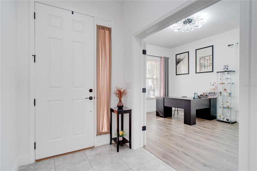 An entryway with a white door leads into a home office with wood-look flooring — 15755 SWEET LIMETTA DRIVE, WINTER GARDEN, FL