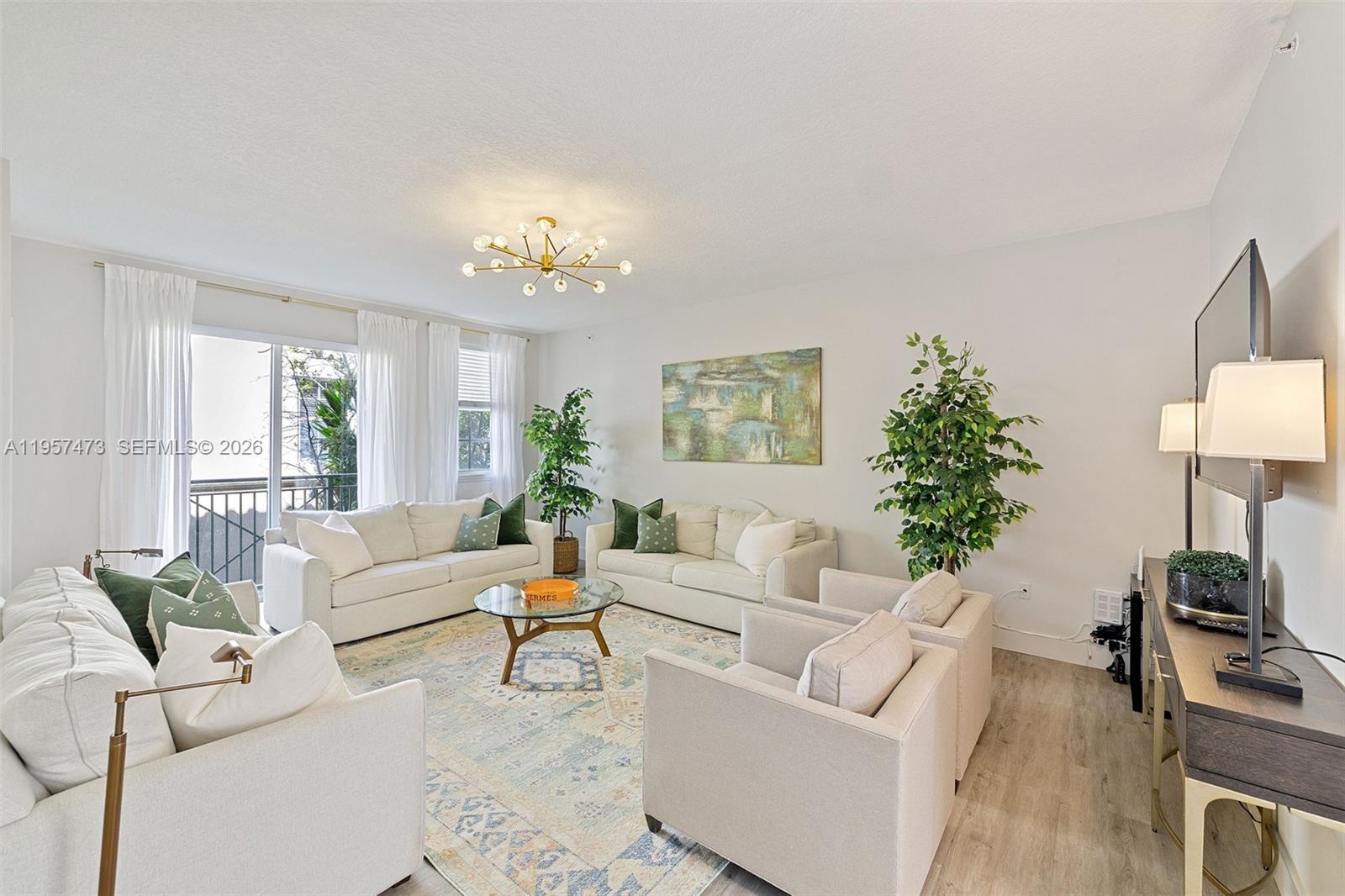 A bright living room features white sofas, armchairs, a glass coffee table, and a rug — 2067 S Ocean Dr, Hallandale Beach FL 33009, HALLANDALE BEACH, FL