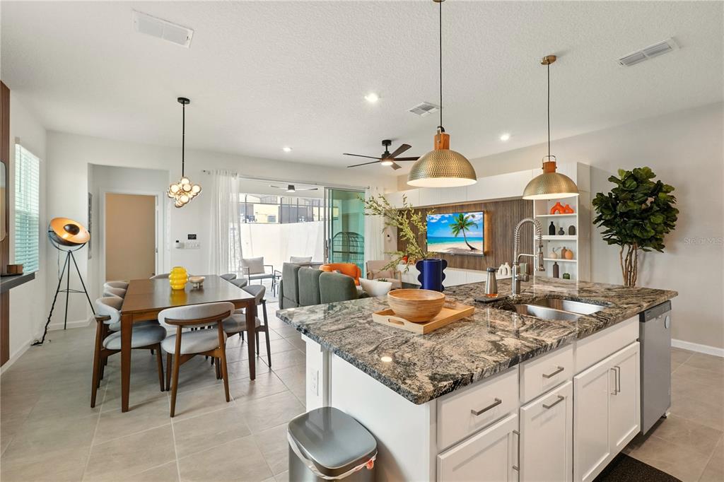A kitchen with granite countertops and a dining area overlooking a living room and patio — 2306 ZABALLINA PLACE, KISSIMMEE, FL