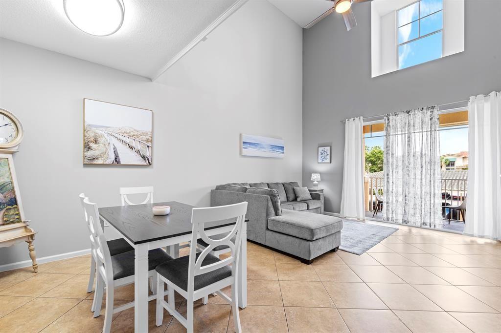 A living and dining area features vaulted ceilings, tile flooring, and a sliding glass door — 4784 S Central Boulevard # 22, Jupiter FL 33458, JUPITER, FL