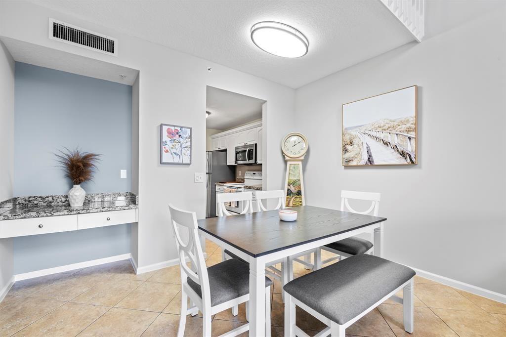 A dining area features a dark wood table, white chairs, a bench, and a built-in desk — 4784 S Central Boulevard # 22, Jupiter FL 33458, JUPITER, FL