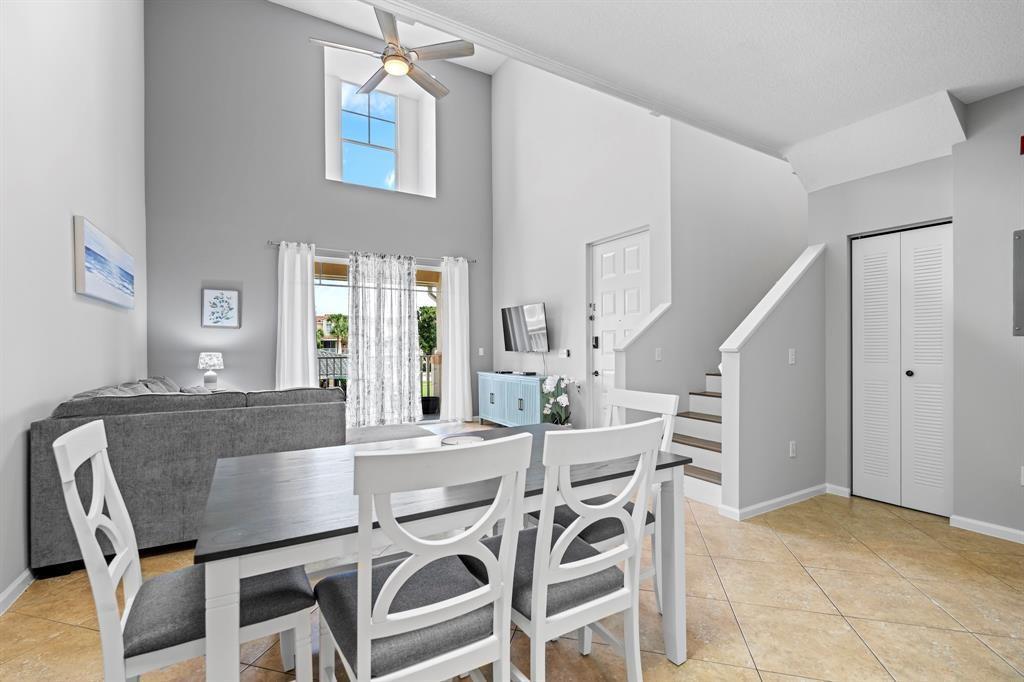 A dining area with white chairs sits in front of a living room with high ceilings — 4784 S Central Boulevard # 22, Jupiter FL 33458, JUPITER, FL