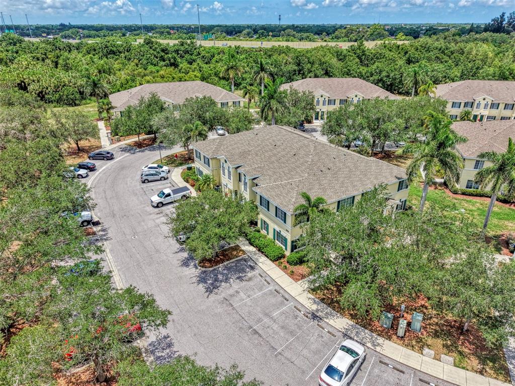 An aerial view shows a multi-story apartment building surrounded by trees and parking lots — 305 CAPE HARBOUR LOOP UNIT 104, BRADENTON, FL