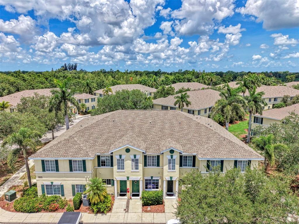 An aerial view of a two-story apartment building with a tan exterior and palm trees — 305 CAPE HARBOUR LOOP UNIT 104, BRADENTON, FL