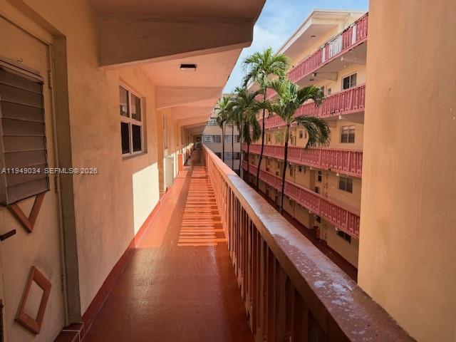An outdoor walkway with a railing overlooks a multi-story apartment building with palm trees — 215 SE 3rd Ave # 307B, Hallandale Beach FL 33009, HALLANDALE BEACH, FL