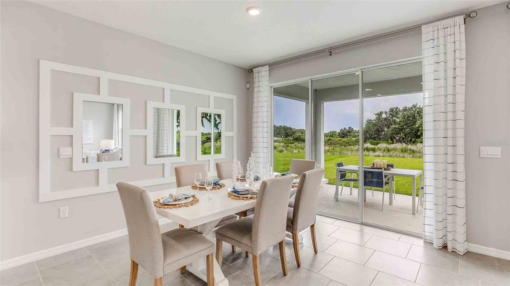 A dining room features a white table, upholstered chairs, a decorative wall mirror, and sliding doors — 35630 LOWERY TRAIL, ZEPHYRHILLS, FL
