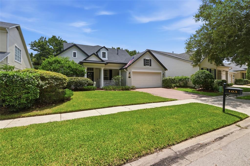 A single-story house with a white garage, a front porch, and a green lawn — 103 ASTERBROOKE DRIVE, DELAND, FL