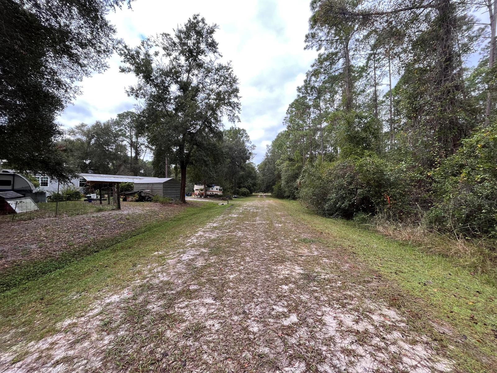 A dirt path leads through a wooded area past a residential property with outbuildings — 108 SE 5th Street, FL 32139, FL