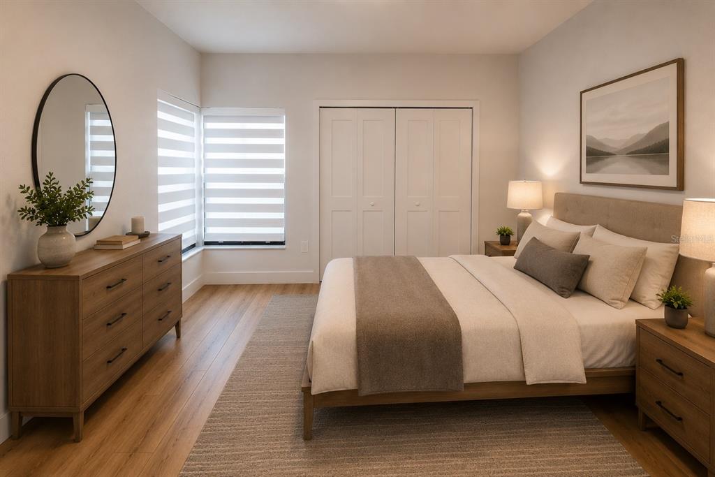 A bedroom features a wooden dresser, a bed with neutral bedding, and a large round mirror — 4704 CHEVY PLACE UNIT 180, ORLANDO, FL