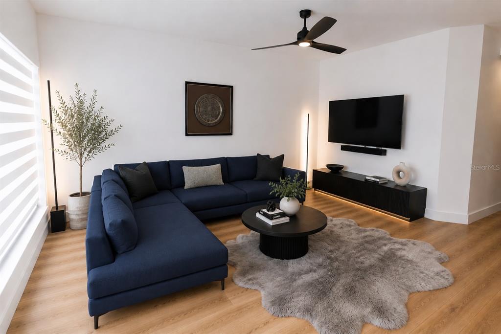 A modern living room features a navy blue sectional sofa, a round coffee table, and television — 4704 CHEVY PLACE UNIT 180, ORLANDO, FL