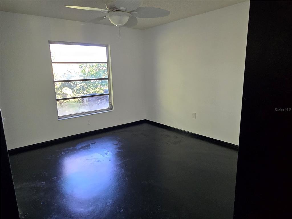 An empty bedroom features white walls, a ceiling fan, and dark flooring — 2974 CAPTIVA GARDENS DRIVE UNIT 17, SARASOTA, FL