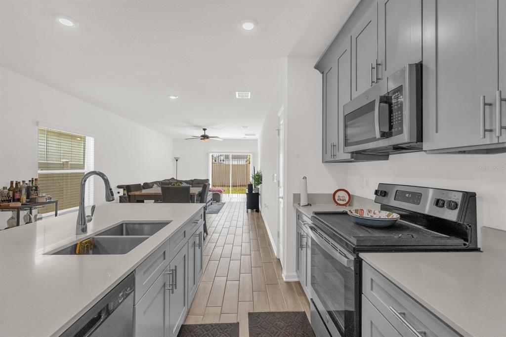 A kitchen with gray cabinets and white countertops overlooks an open-concept living and dining area — 555 JETT LANE, DAVENPORT, FL