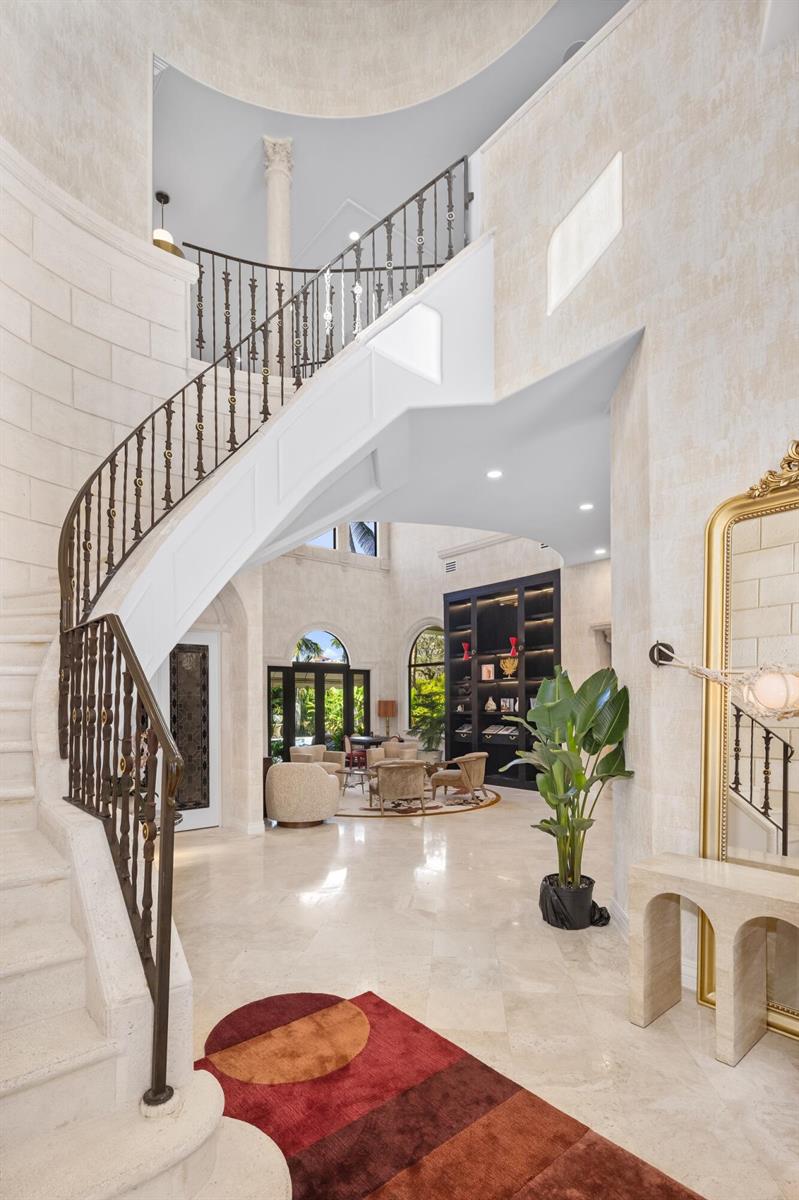 A grand foyer features a curved stone staircase with iron railings and marble flooring — 422 Addison Park Lane, Boca Raton FL 33432, BOCA RATON, FL
