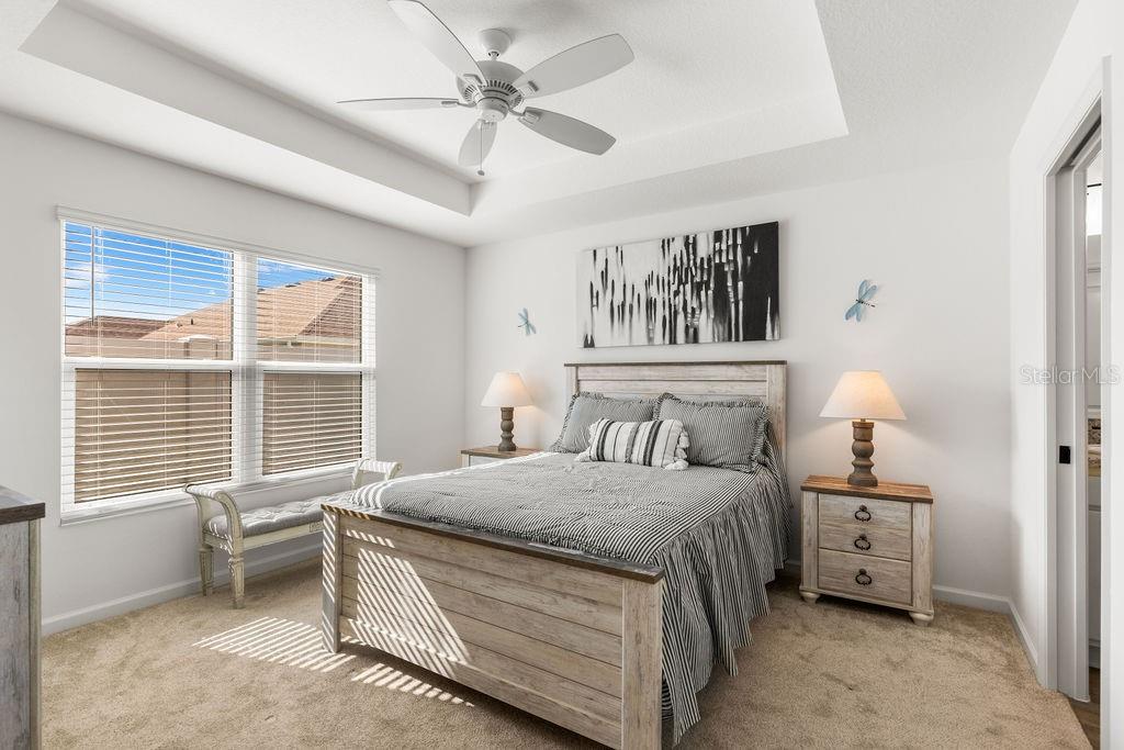 A bedroom features a queen bed, a ceiling fan, and a window with white blinds — 2938 CHIMBORAZO WAY, THE VILLAGES, FL