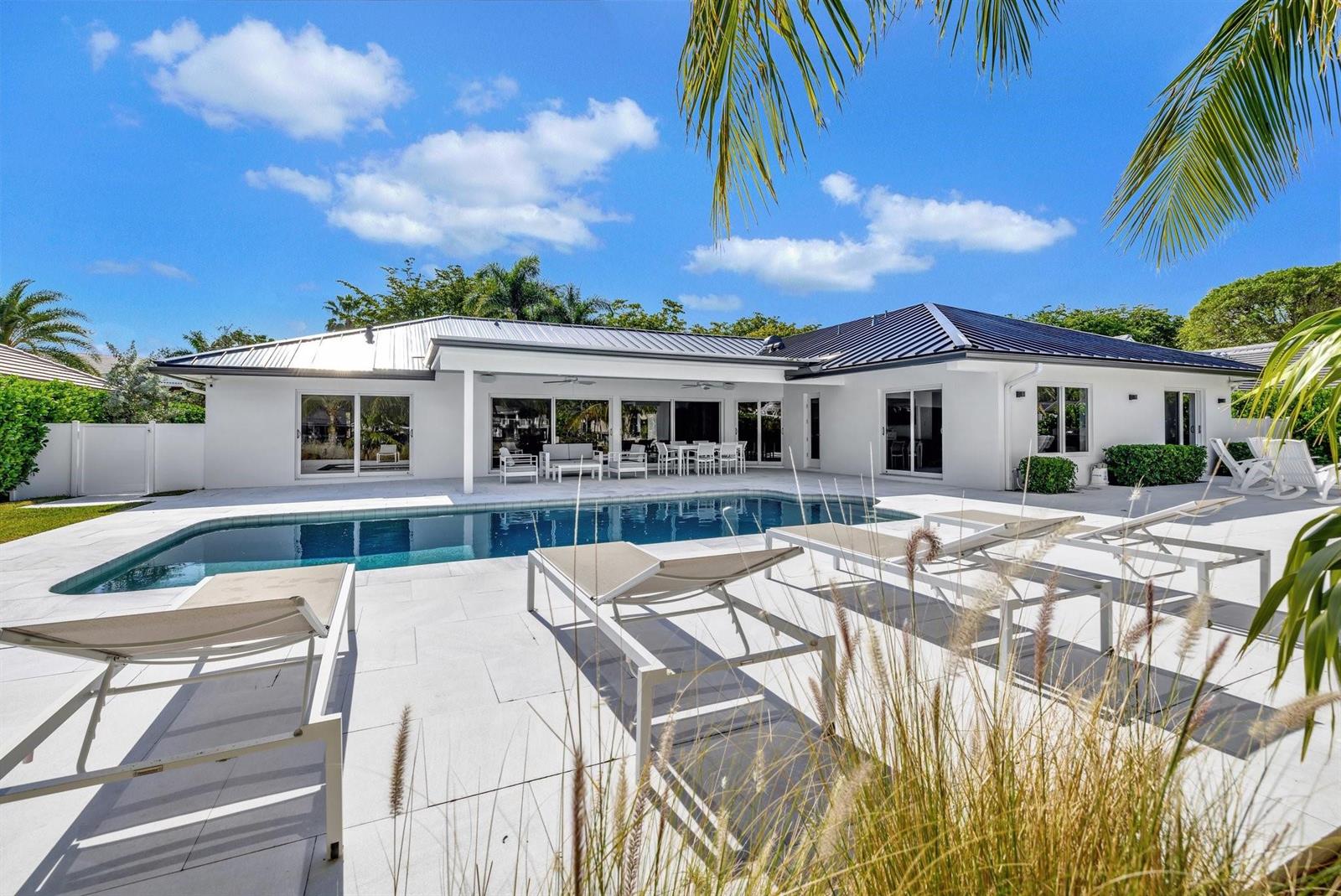 A white house with a metal roof overlooks a swimming pool and patio with lounge chairs — 41 S Compass Drive, Fort Lauderdale FL 33308, FORT LAUDERDALE, FL
