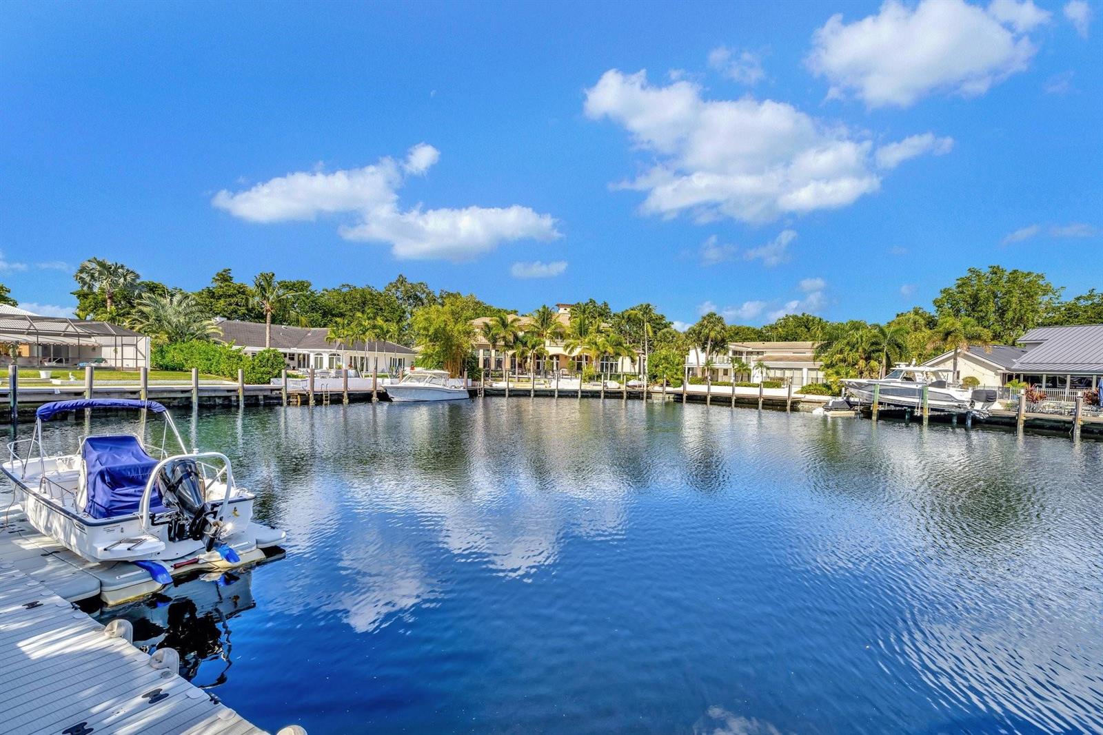 A canal view shows a boat docked at a pier with houses in the background — 41 S Compass Drive, Fort Lauderdale FL 33308, FORT LAUDERDALE, FL