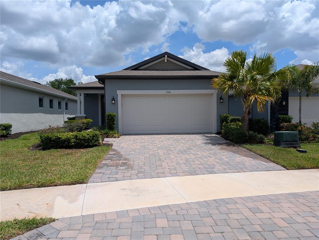 A single-story house with a gray exterior, a two-car garage, and a paved driveway — 3794 MAXWELL PARK DRIVE, SUN CITY CENTER, FL