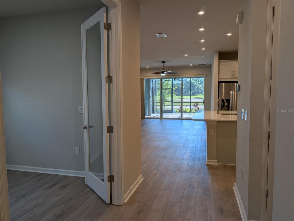 A view from a doorway into an open-concept living area with wood-look tile flooring — 3794 MAXWELL PARK DRIVE, SUN CITY CENTER, FL