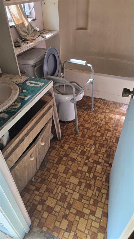 A small, dated bathroom features a vanity, a toilet with safety rails, and a bathtub — 220 MOUNT PLEASANT ROAD, NOKOMIS, FL