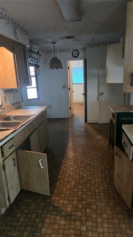 A kitchen with wood cabinets, a double sink, and checkered flooring in need of renovation — 220 MOUNT PLEASANT ROAD, NOKOMIS, FL