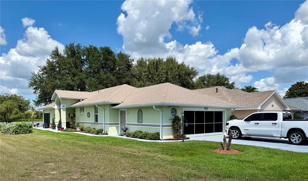 A light green single-story house with a two-car garage and a white pickup truck parked outside — 21932 ROYAL ST GEORGES LANE, LEESBURG, FL