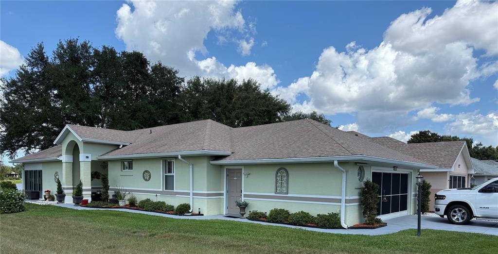 A light green single-story house with a shingled roof and a white pickup truck parked — 21932 ROYAL ST GEORGES LANE, LEESBURG, FL
