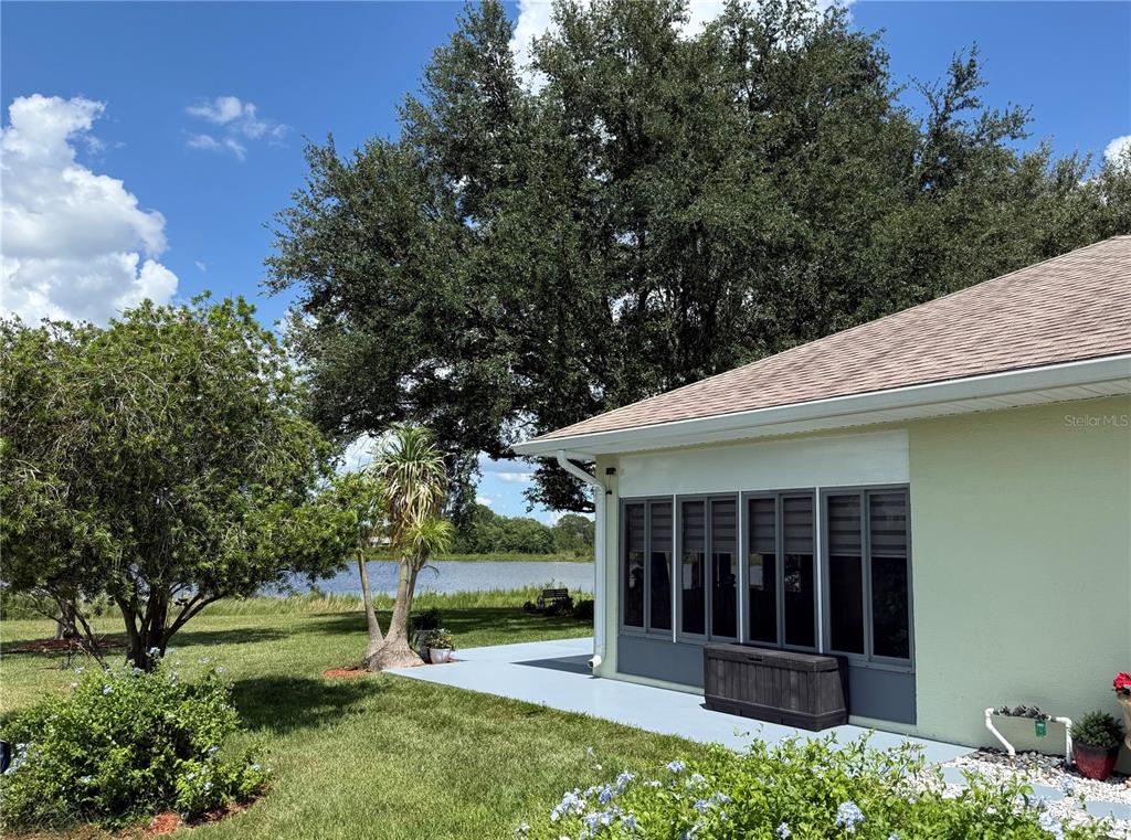 A view of a house exterior with a screened-in porch, a patio, and a lake — 21932 ROYAL ST GEORGES LANE, LEESBURG, FL