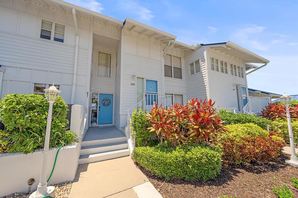 The exterior of a two-story white building features a blue front door and landscaping — 851 AUDUBON DRIVE UNIT 851, BRADENTON, FL