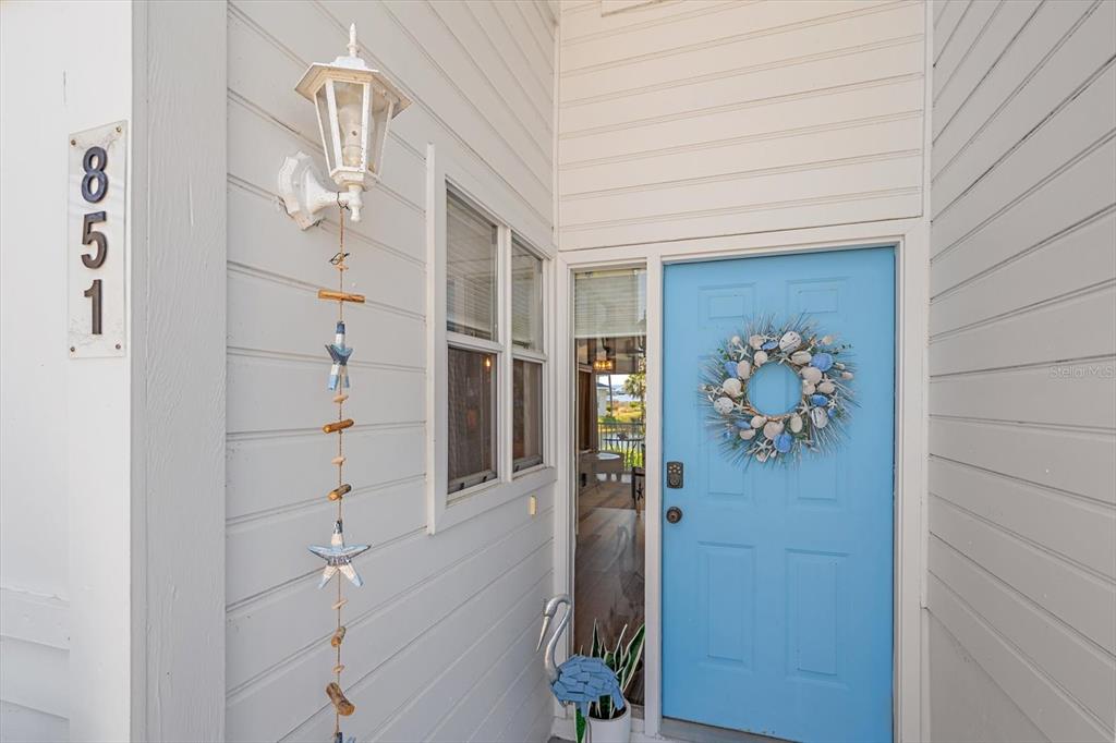 A light blue front door with a seashell wreath sits beside a white exterior wall — 851 AUDUBON DRIVE UNIT 851, BRADENTON, FL