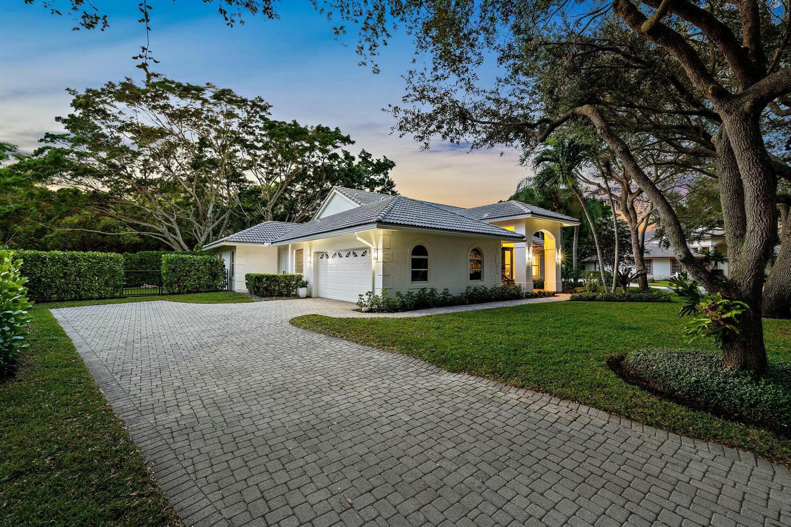 A single-story house with a paved driveway, white stucco exterior, and a tiled roof — 9927 SE Canary Palm Way, Jupiter FL 33469, JUPITER, FL