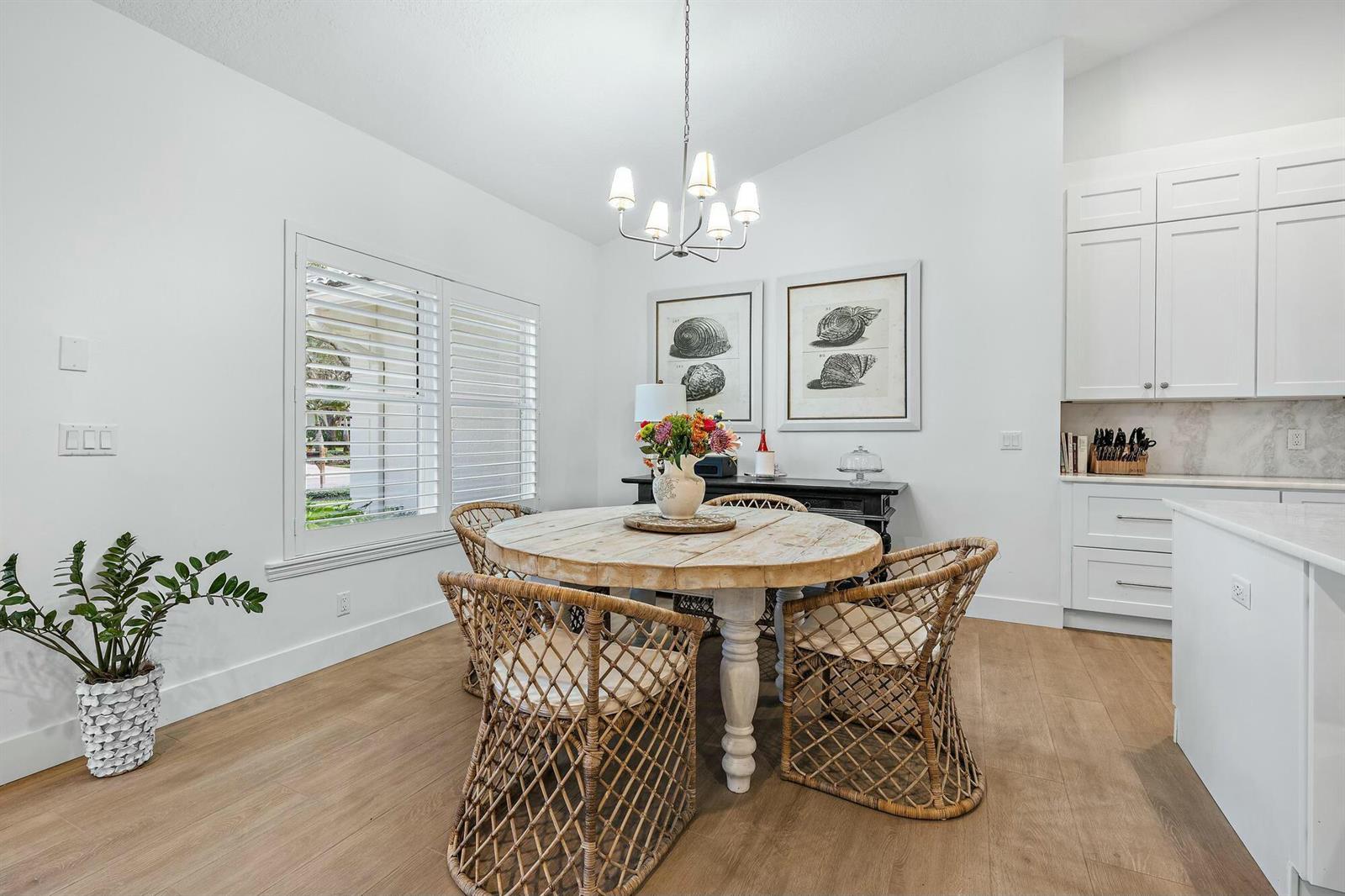 A dining area features a round wooden table, wicker chairs, and white cabinetry — 9927 SE Canary Palm Way, Jupiter FL 33469, JUPITER, FL