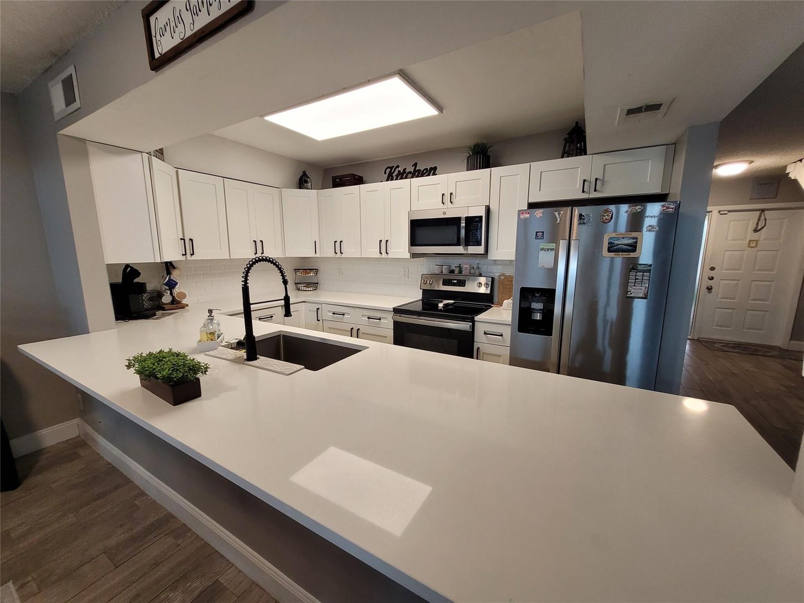 A kitchen features white cabinets, stainless steel appliances, and a large white quartz island countertop — 1146 N University Drive, Plantation FL 33322, PLANTATION, FL