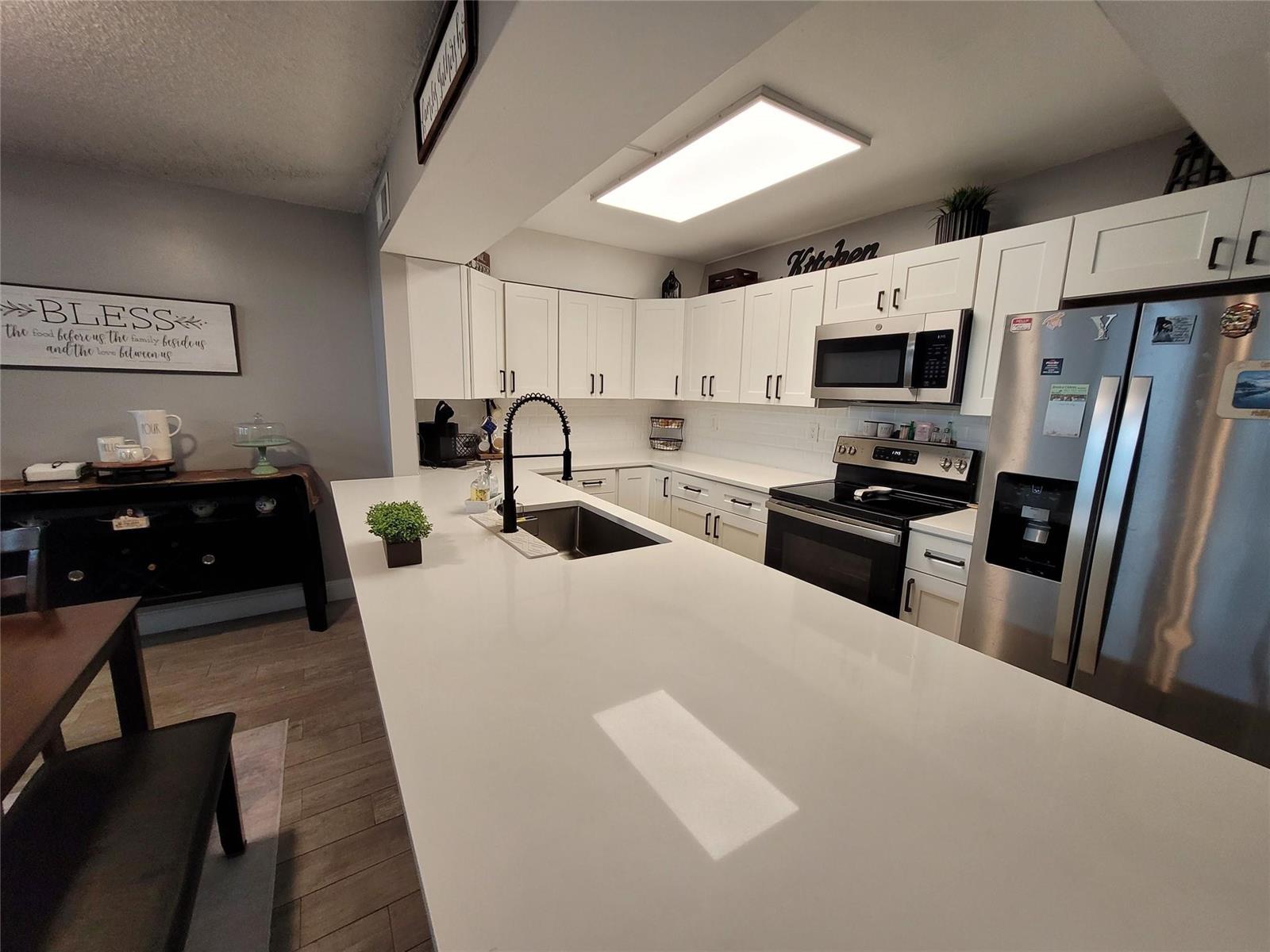 A kitchen features white cabinets, stainless steel appliances, and a large white quartz island — 1146 N University Drive, Plantation FL 33322, PLANTATION, FL
