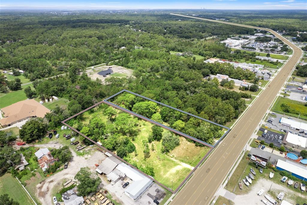 An aerial view shows two adjacent, undeveloped wooded lots bordering a multi-lane road — 6574 W GULF TO LAKE HIGHWAY, CRYSTAL RIVER, FL