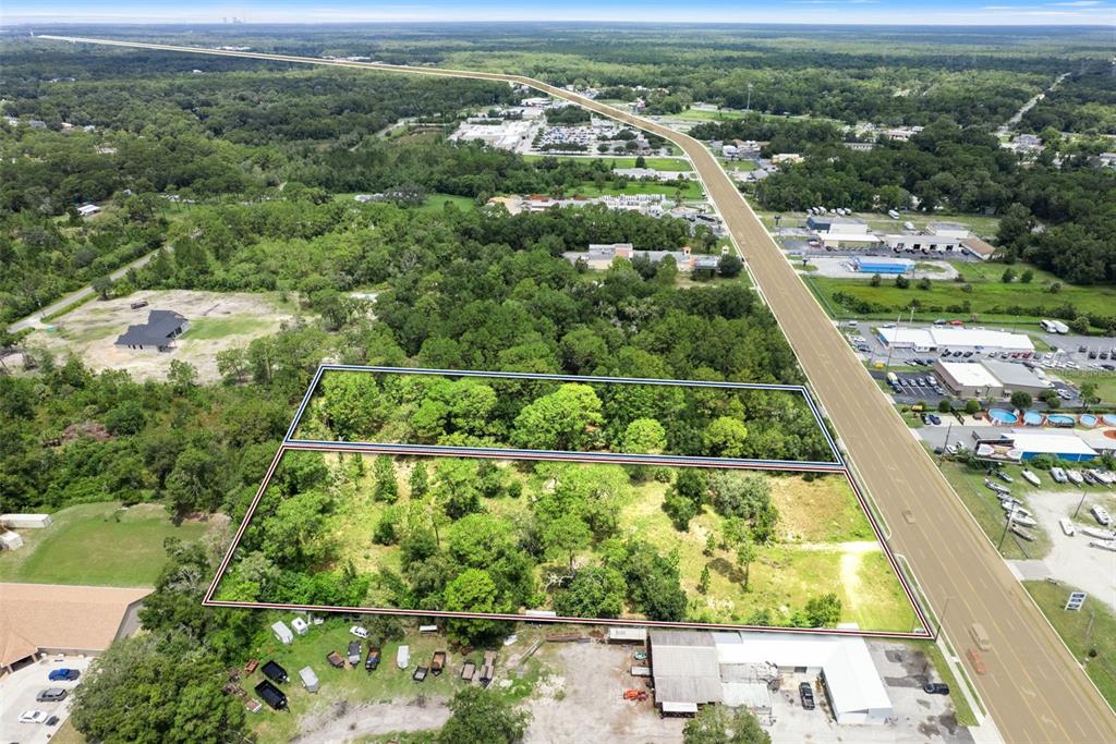 An aerial view shows two adjacent, wooded rectangular lots bordering a multi-lane highway — 6574 W GULF TO LAKE HIGHWAY, CRYSTAL RIVER, FL