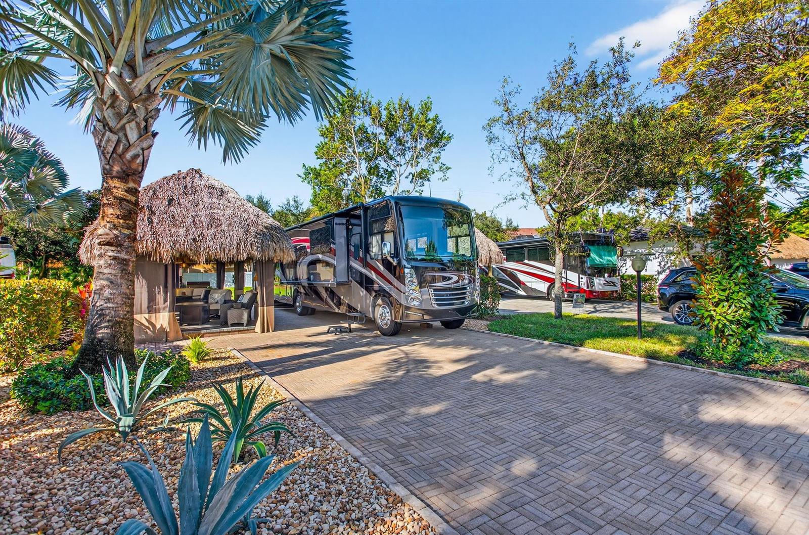 A paved driveway features a large motorhome parked next to a thatched-roof tiki hut — 6 S Cortez Drive # 6, Margate FL 33068, MARGATE, FL
