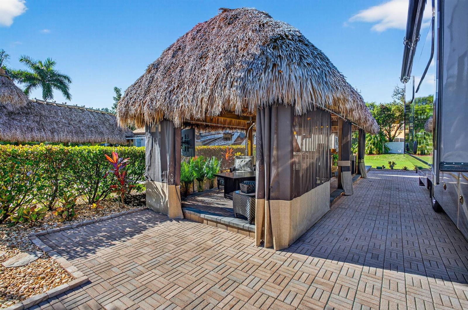 A thatched-roof tiki hut sits on a paved patio next to a parked recreational vehicle — 6 S Cortez Drive # 6, Margate FL 33068, MARGATE, FL
