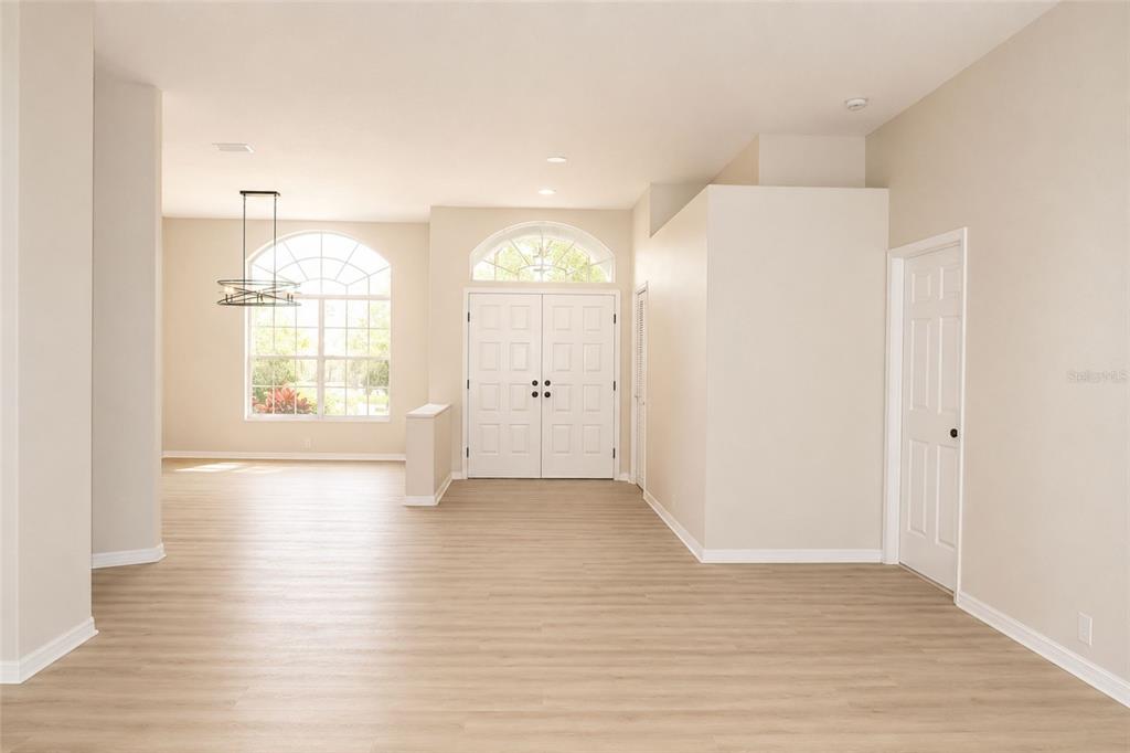 An entryway with light wood-look flooring leads to a double front door and arched windows — 17316 HIALEAH DRIVE, ODESSA, FL