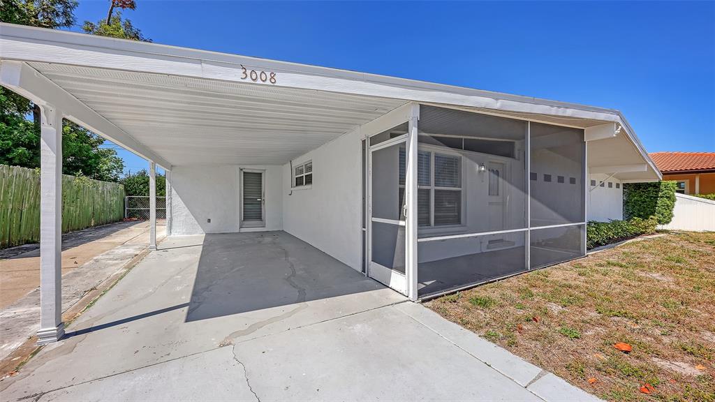 A white house exterior features a covered carport and a screened-in front porch area — 3008 BOWDOIN PLACE, BRADENTON, FL