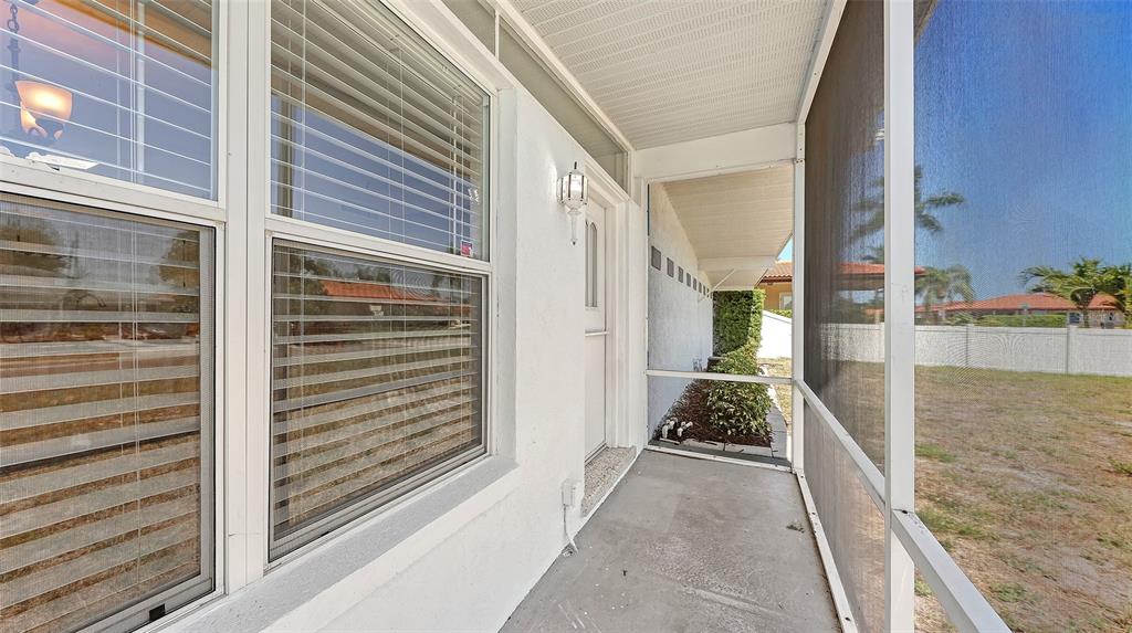 A screened-in porch with a white door, windows with blinds, and a concrete floor — 3008 BOWDOIN PLACE, BRADENTON, FL