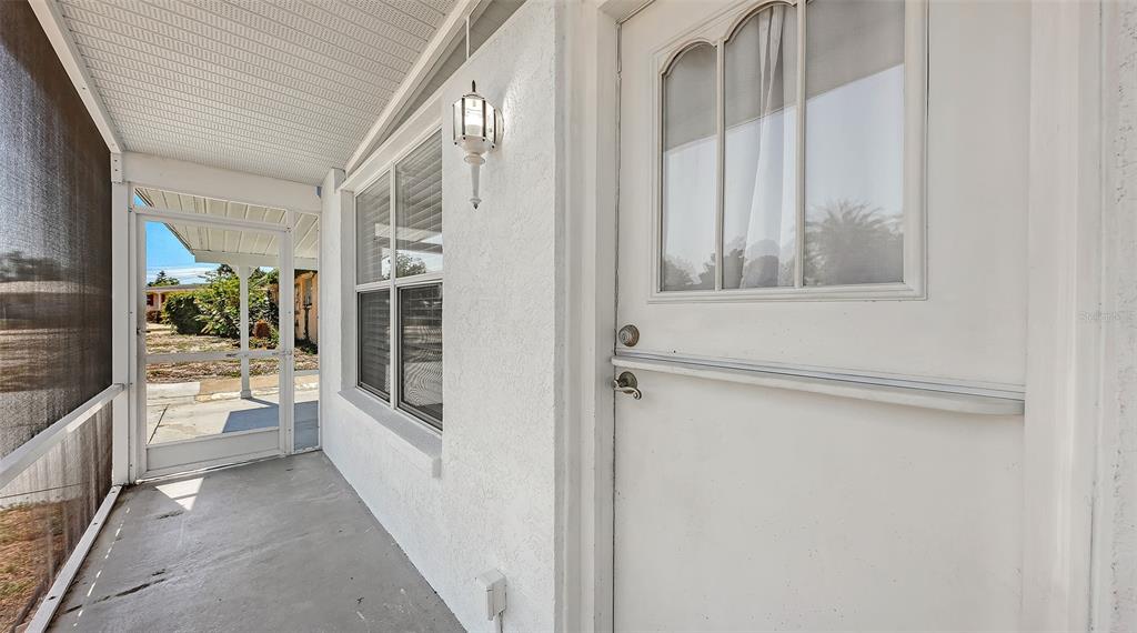 A covered porch with a screen door, a white entry door, and a window — 3008 BOWDOIN PLACE, BRADENTON, FL