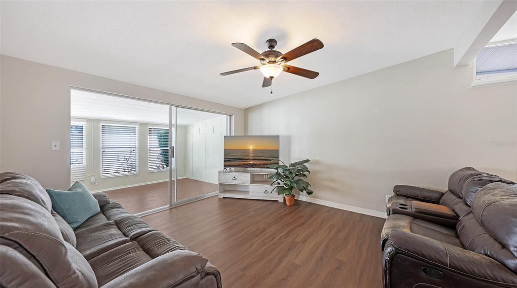 A living room features brown leather sofas, a television on a stand, and wood-look flooring — 3008 BOWDOIN PLACE, BRADENTON, FL