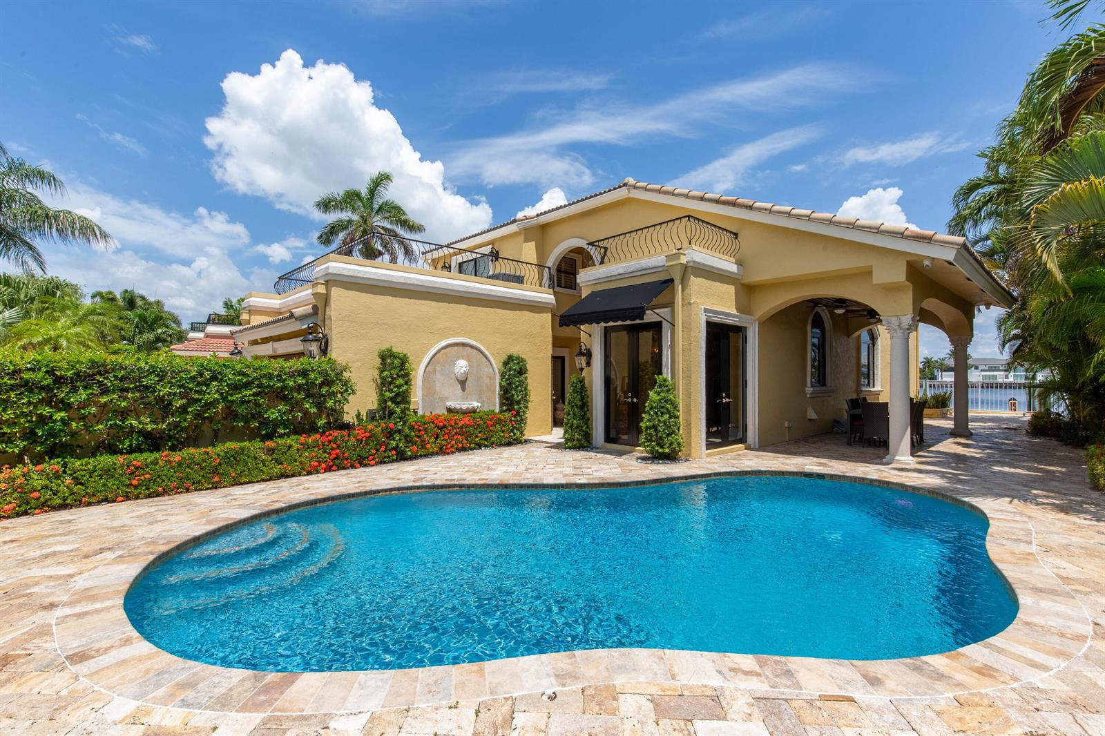 A yellow two-story house features a swimming pool, stone patio, and a wall fountain — 529 Pelican Way, Delray Beach FL 33483, DELRAY BEACH, FL