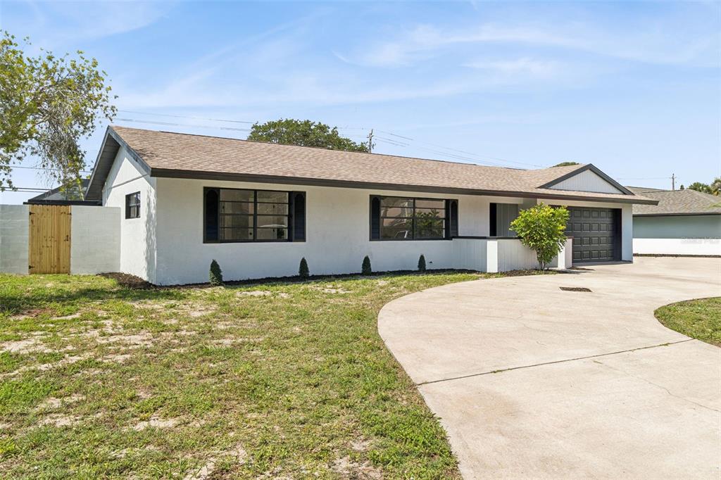 A single-story white house with a brown shingled roof, dark trim, and a concrete driveway — 381 E RIVIERA BOULEVARD, INDIALANTIC, FL
