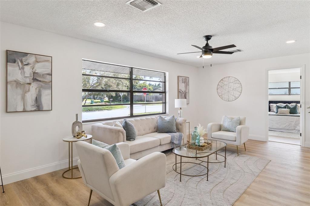 A bright living room features a light-colored sofa, two armchairs, a coffee table, and wood-look flooring — 381 E RIVIERA BOULEVARD, INDIALANTIC, FL