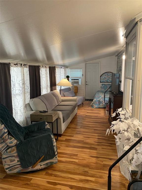 A sunroom features wood-look flooring, a sofa, a recliner, and a bed in the background — 1300 N RIVER ROAD UNIT W 86, VENICE, FL